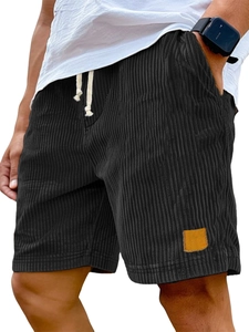 Close-up of black corduroy casual shorts showing textured fabric and brown leather patch