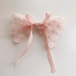 Detailed view of pink lace hair bow with floral embroidery, sequins and pearls