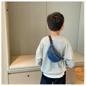 Kids denim crossbody bag in washed blue shown on back with black strap and metal zipper
