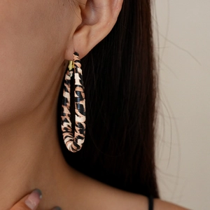 Close-up of leopard print wrap hoop earrings on a model showing vintage aesthetic