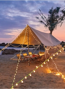 Close-up of LED string lights decorating a campsite with a tent and canopy at sunset