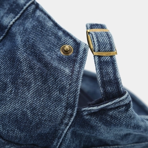 Détail du béret en jean avec texture sergé et boucle de réglage en laiton vintage