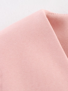 Dettaglio ravvicinato della trama del tessuto twill rosa della giacca blazer da donna