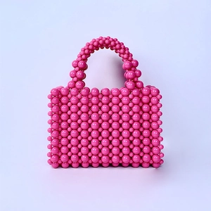 Detail of pink acrylic pearl beads on a handmade woven handbag with beaded handle
