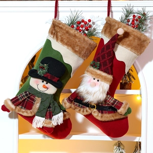 Detail of Christmas plush socks with snowman and Santa patterns hanging on a fireplace
