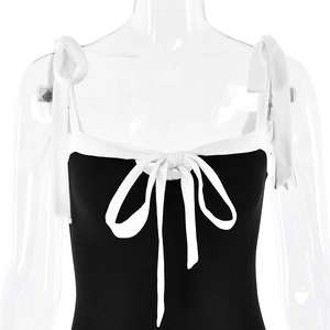 Detailed view of black and white contrast dress with adjustable straps and front bow detail