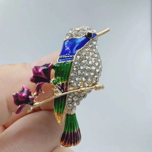Elegant enamel hummingbird brooch with vibrant crystals and purple flowers on gold base