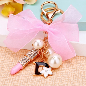 Detailed macro view of rhinestone lipstick pendant with pink bow and pearls on a keychain