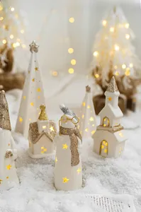 Close-up of lighted white ceramic Christmas houses and snowman with star cutouts
