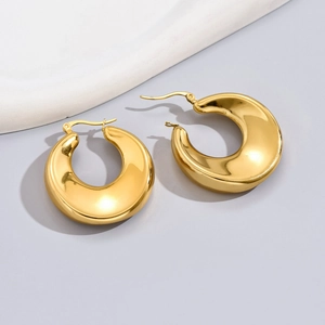 Detailed close-up of golden hollow teardrop hoop earrings with mirror polished finish