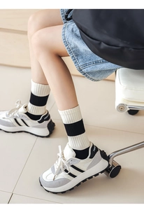 Detail of striped cream mid-calf cotton socks paired with tri-color athletic sneakers