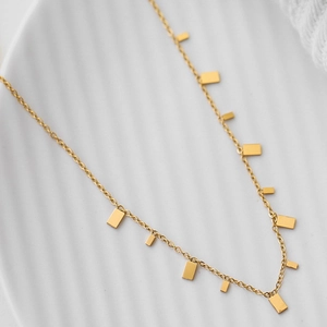 Close-up of golden double-layer chain with minimalist rectangular metal pendants