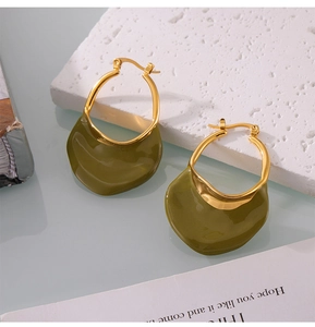 Macro shot of olive green enamel wave charms on gold hooks atop a stone display