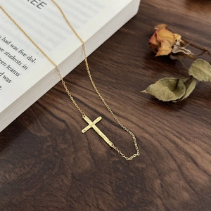 Macro detail of vintage gold cross necklace with hammered texture on a wooden desk