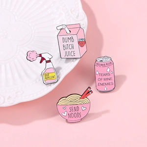 Detail of pink enamel pins including strawberry milk and ramen on a ceramic plate