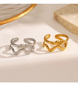 Detail of silver and gold wave rings with heart charm on a minimalist stone background