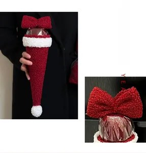 Close-up of red plush cone gift bag with a bow and white pom-pom for Christmas apples