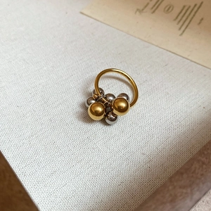 Artistic detail of gold and silver plated metal drop ring on a textured fabric surface