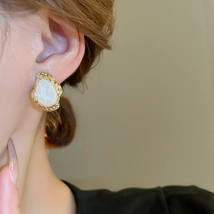 Close-up of vintage geometric gold-tone stud earrings worn by a model in a minimal setting