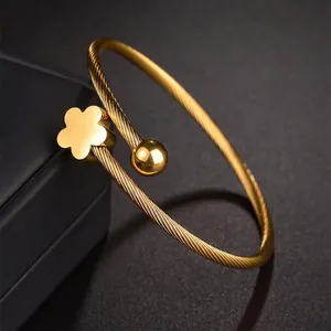 Bracelet torsadé en acier titane doré avec fleur à cinq pétales polie et embouts boules