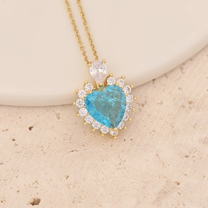 Detail of gold heart necklace with light blue stone and clear zircon crystals