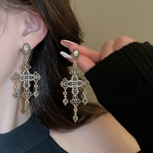 Macro detail of French vintage gold cross earrings with pearls and green gemstones