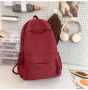 Detail eines burgunderfarbenen Nylon-Rucksacks mit gewebten Reißverschlussgriffen