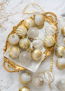 Close-up of festive 6cm gold and white glitter Christmas baubles on a mirror tray
