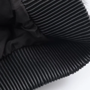 Détail du manteau en similicuir noir avec poignets élastiques plissés et doublure intérieure