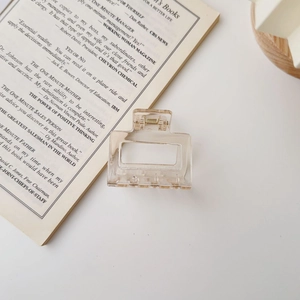 Detail of square transparent marble hair claw clip with metal spring on a white desk
