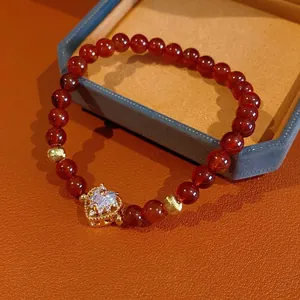Garnet red agate bracelet with a golden heart zircon pendant on a textured leather base