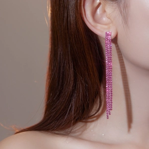 Detailaufnahme langer Ohrhänger mit rosa Strasssteinen und funkelnden Kristallschichten