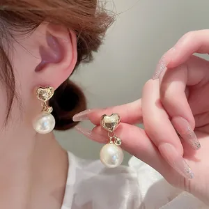 Close-up of elegant gold heart studs and large white pearls for a French vintage look