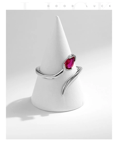 Detailed view of silver snake ring with a pear-cut red gemstone on a studio stand