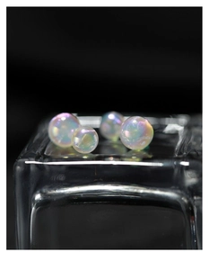 Macro detail of four round iridescent faux pearls with rainbow luster on glass base