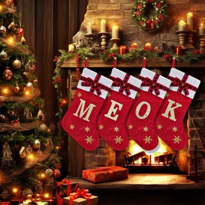 Set of four red knitted Christmas stockings with gold embroidered letters on a mantel