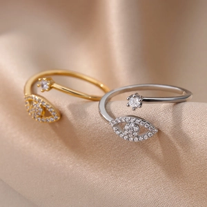 Close-up of Evil Eye adjustable rings with inlaid cubic zirconia on satin fabric