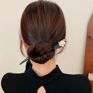 Détail d'une épingle à cheveux fleur en bois portée en chignon au style rétro chic