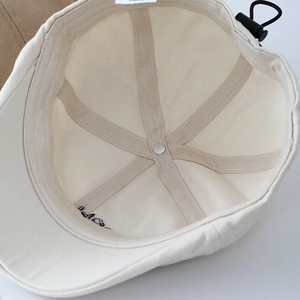 Détail intérieur du béret en toile écrue avec cordon de serrage et boucle réglable