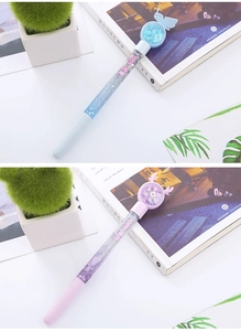 Close-up of glitter liquid pens with butterfly and reindeer charms on a desk