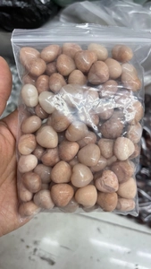 Macro view of polished pink heart-shaped crystal stones in a clear storage bag