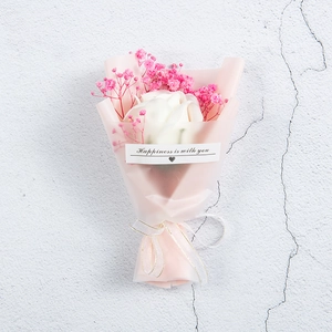 Close-up of mini white rose and pink baby's breath bouquet in semi-transparent wrapping