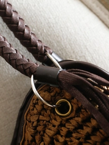 Handcrafted brown woven straw shoulder bag with durable leather rope straps and metal rings