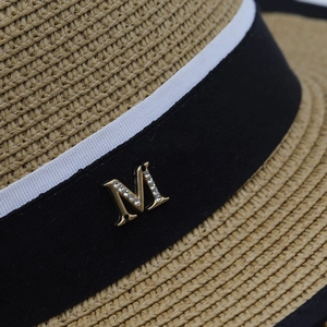 Dettaglio cappello di paglia con nastro bianco e nero e logo M con cristalli