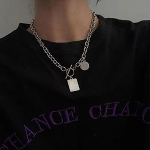 Detail of silver titanium steel chunky chain necklace with double geometric pendants on model