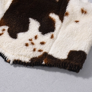 Detailaufnahme der weichen braun-weißen Fleece-Struktur mit Kuhmuster und Nahtkante