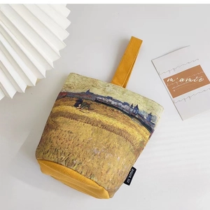 Close-up of canvas bucket bag with Van Gogh Harvest painting print and yellow strap