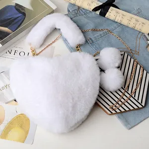 Detail of white heart-shaped faux fur bag with golden chain and plush pom-poms