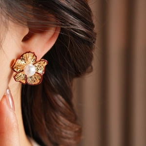 Nahaufnahme von Vintage-Blumenohrringen mit Perlen, getragen an einem Frauenohr