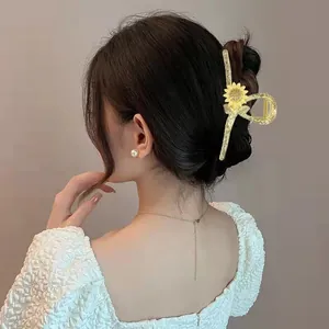 Detail of a large gold metal sunflower hair claw clip worn on dark hair for styling